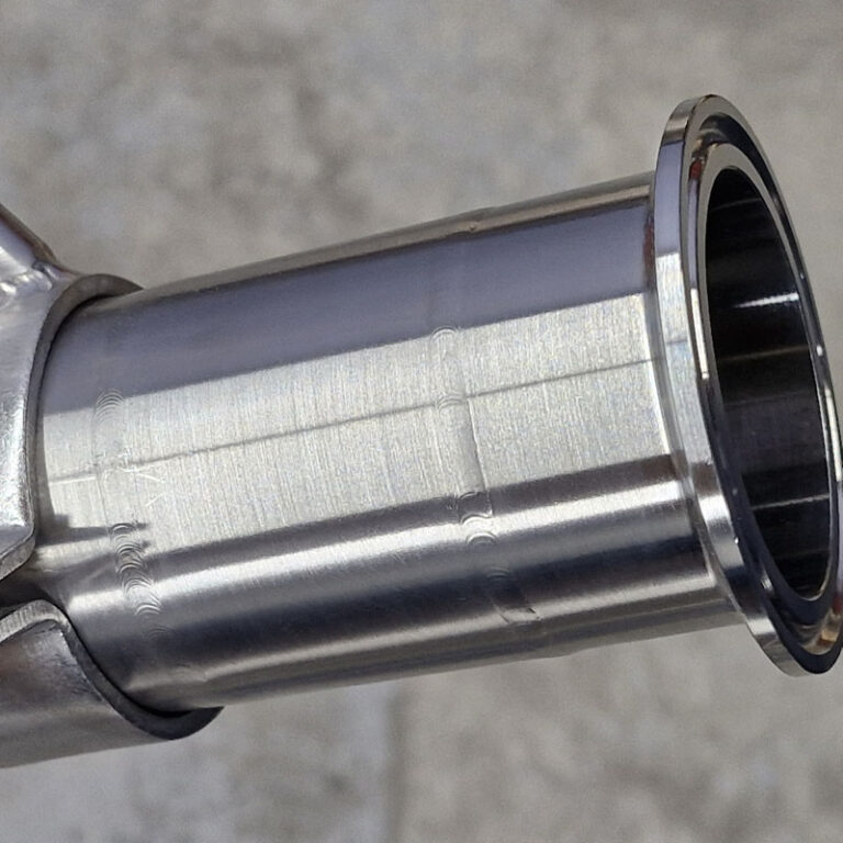 Close-up view of a polished stainless steel pipe joint with smooth welds and a sanitary finish.